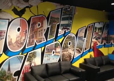 An internal mural with large 3D text reading "North Carolina". Inside each letter are images from western north Carolina cities and landmarks from different time periods.