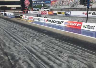 Series of motor sports logos spanning several lane barriers on a NASCAR track.