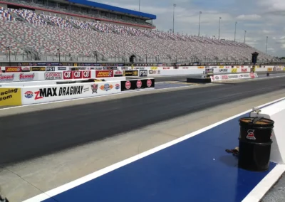 Series of motor sports logos spanning several lane barriers on a NASCAR track.