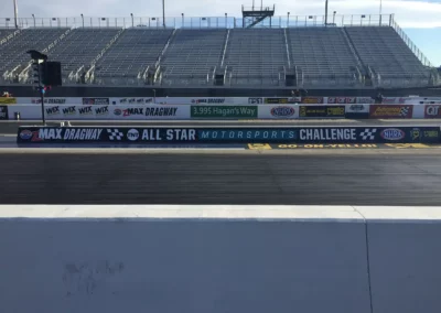 Series of motor sports logos spanning several lane barriers on a NASCAR track.